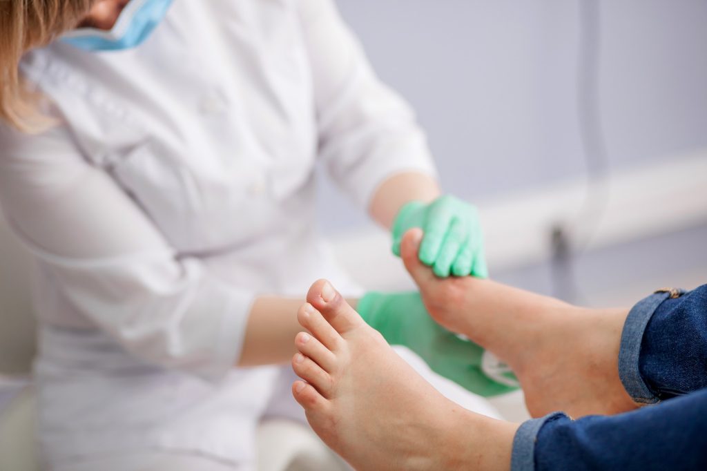 Doctor, el podólogo examina el pie.